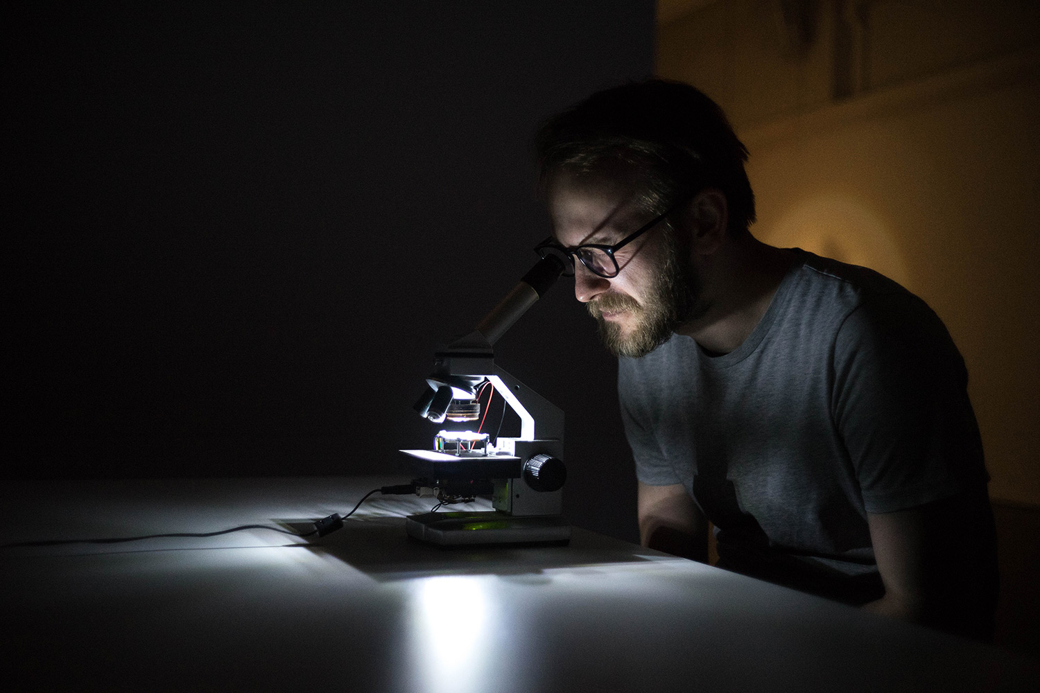 person sitting at a table looking through a microscope