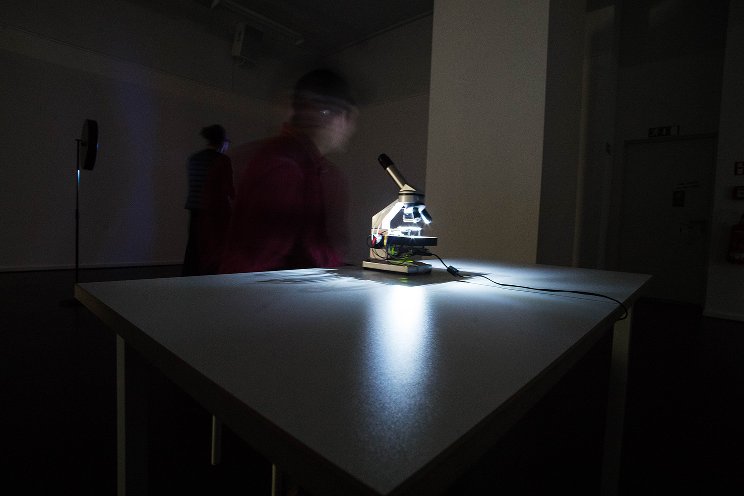 long exposure of person sitting in front of microscope in an exhibition space