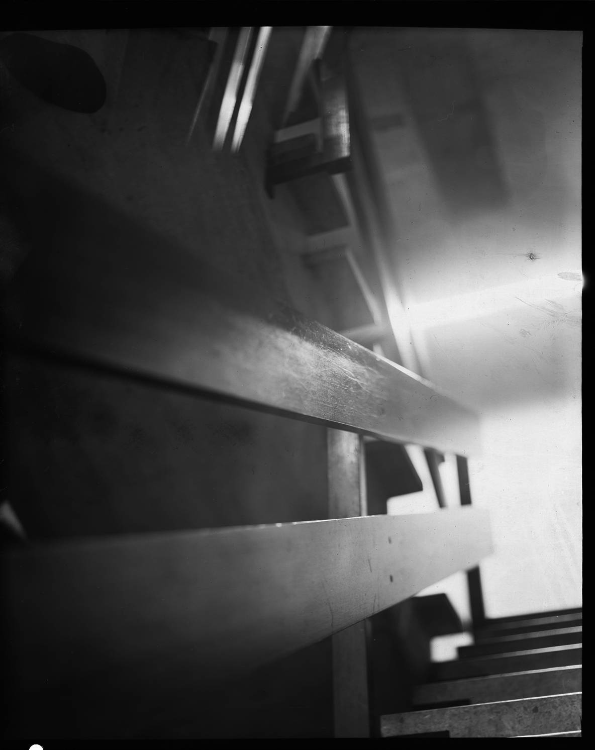 a handrail in a staircase with lots of scratchmarks in high contrast analog black and white